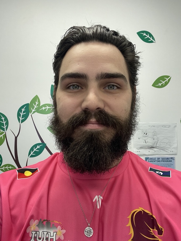 Max Jessop, occupational therapist, wears a Pamela Mam pink shirt, smiling with a background containing pictures of leaves. :)