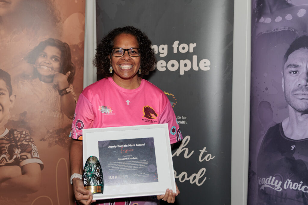 Lizzy Knudsen smiling and holding her Pamela Mam Award
